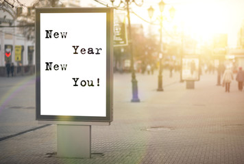 new year new you! text on an advertising banner, city street, sun rays