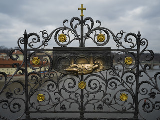 Fototapeta na wymiar Iron forged grid with St. John of Nepomuk carving on the Charles Bridge, Prague, Czech Republic