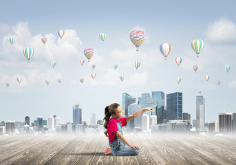 Concept of careless happy childhood with girl pointing at something