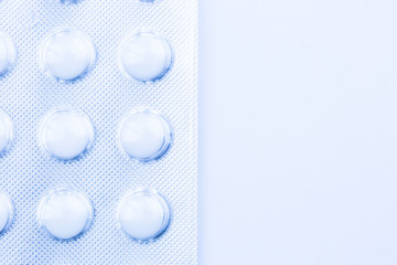 White pills in packaging on the white background (macro concept)