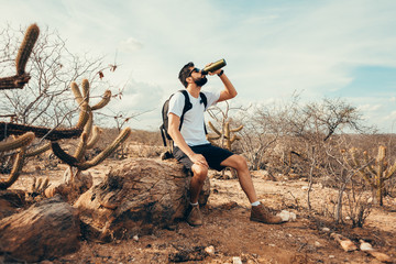 Tired hiker drinks water from a bottle