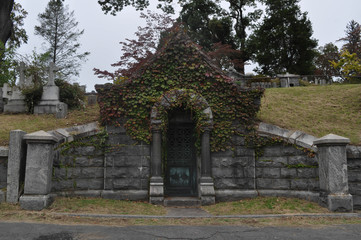 Old Stone Mausoleum Overgrown with Ivy in a Cemetery