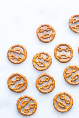 Emoji shaped pretzels on a white marble background. 