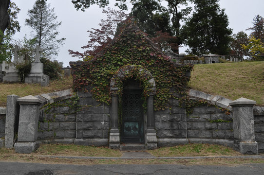 Old Stone Mausoleum Overgrown With Ivy In A Cemetery