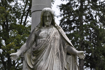 Fototapeta premium Statue of Jesus Looking Down Upon a Grave