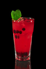 Glass of currant mors, berry compote on black background with reflection