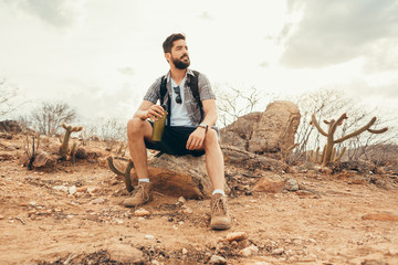 Young man relaxing and enjoying the ambience after long hike in the desert - Powered by Adobe