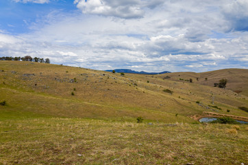 Fototapeta na wymiar Rural mountain landscape with fields, trees, low hills