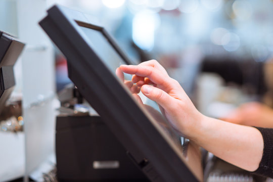 Young woman hand doing process payment on a touchscreen cash register, finance concept (color toned image)