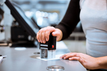 Young woman hand doing process payment, getting stamp with sale to a receipt in the huge shopping center, finance concept (color toned image)