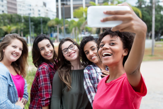 African american woman taking selfie with group of international girlfriends
