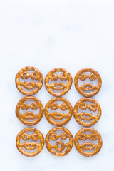 Smiley face shaped pretzels on a white marble background 