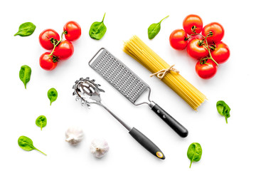 Cooking italian pasta. Spaghetti, tomatoes, garlic, basil and cookware on white background top view