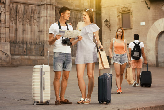 Family couple with luggage checking direction in map