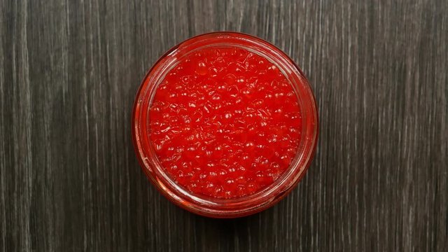 Opening jars with red caviar. Women's hands open a lid from a jar of red caviar. Top view