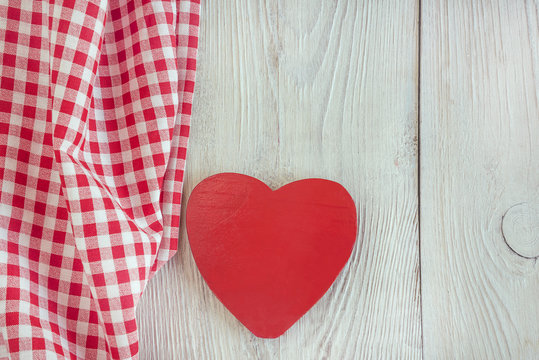 red and white checkered napkin and red wooden heart on white rustic background