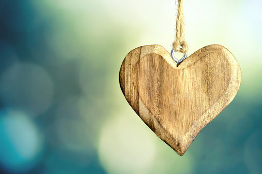Wooden hanging heart on green bokeh background with copy space