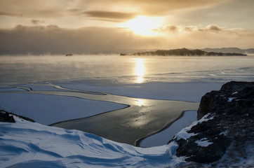 Ice floes floating on the fog water in the lake Baikal. Sunset