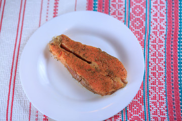 Red salty fish on a white plate on a bright background