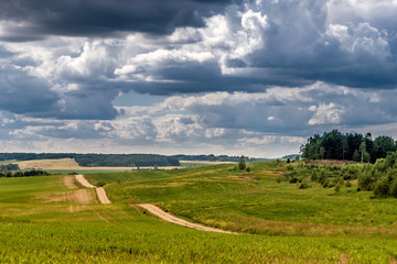 Panoramic view of the sandy serpentine road leaving into the distance and beautiful clouds