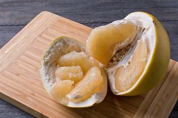 Closeup of sweet pomelo peeled on wooden background.