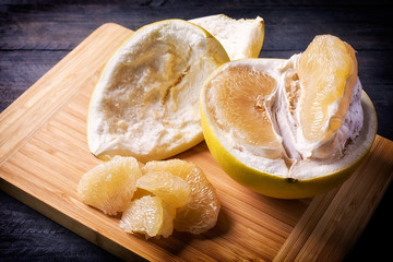Closeup of sweet pomelo peeled on wooden background.