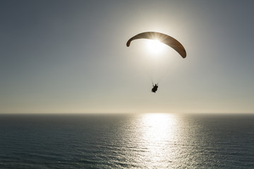 Silhouette of paraglider flying against sky