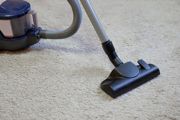 Cleaning the carpet using a vacuum cleaner.