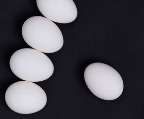 Several white chicken eggs on the black background.