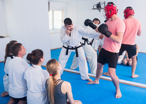 man training new taekwondo holds with adults during class