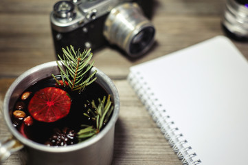 Traditional fruity mulled wine from the old mug, on an old wooden table, on the background of an old camera