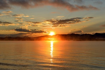 Naklejka premium Sunrise at Yellowstone Lake - A late August morning, the sun rises over the foggy Yellowstone Lake, Yellowstone National Park, Wyoming, USA.