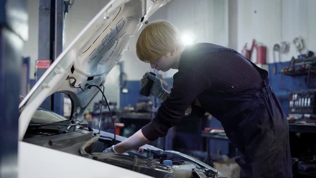auto mechanic is checking internal faults in important car systems and robustness of connections, in automobile repair workshop