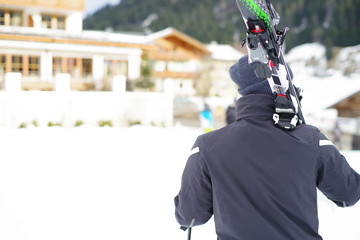 Skiurlaub, Mann trägt Ski auf der Schulter 
