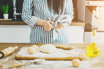 Female hands making dough on kitchen background