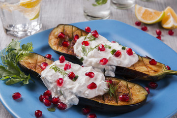 baked eggplants on a plate with cream cheese and pomegranate seeds