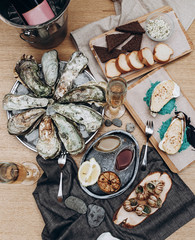 beautiful serving and layout of the table with different seafood: oysters, snails, scallops, sauces, lemons, baguette and croutons with glasses of champagne on a wooden table