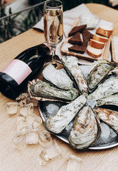 beautiful table setting with oysters on ice with a bottle of champagne on a wooden table - 186919386