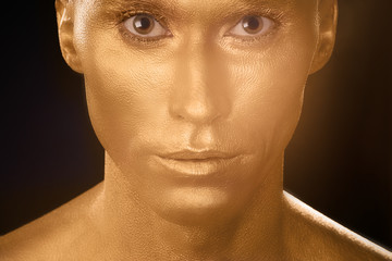 man in gold paint portrait portrait smiling on black background