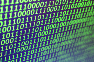 Macro shot of binary code on the monitor of an office computer. The concept of the programmer's work. The flow of digital information strings