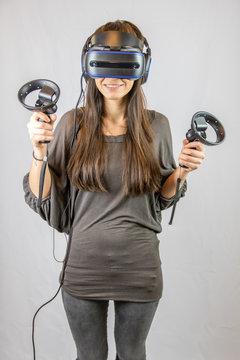 Junge Frau spielt begeistert mit Virtual Reality Datenbrille und Controllern