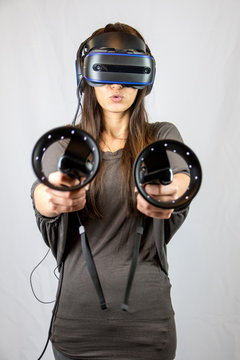 Junge Frau mit Virtual Reality Datenbrille zielt mit  zwei Controllern