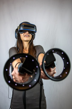 Junge Frau mit Virtual Reality Datenbrille und zwei Controllern (Weitwinkel)