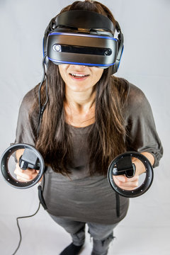 Junge Frau spielt mit Virtual Reality Datenbrille und Controllern (Vogelperspektive)