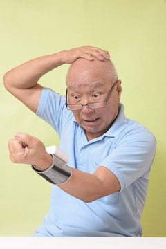 血圧を測定し驚くシニア