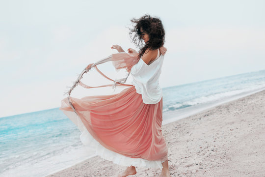 beautiful young stylish woman in pink skirt on the beach