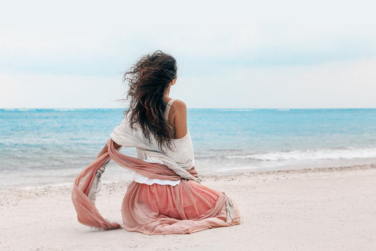 beautiful young stylish woman in pink skirt on the beach