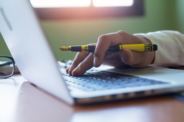 Human hand suing pen with computer, supplies working for business.