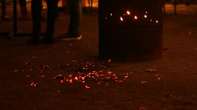 Troubled teenagers hanging out in street at night, warming near fire, gang