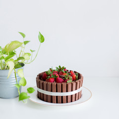 A chocolate cake with kitkat and strawberry on white desk. A very delicious cake.
